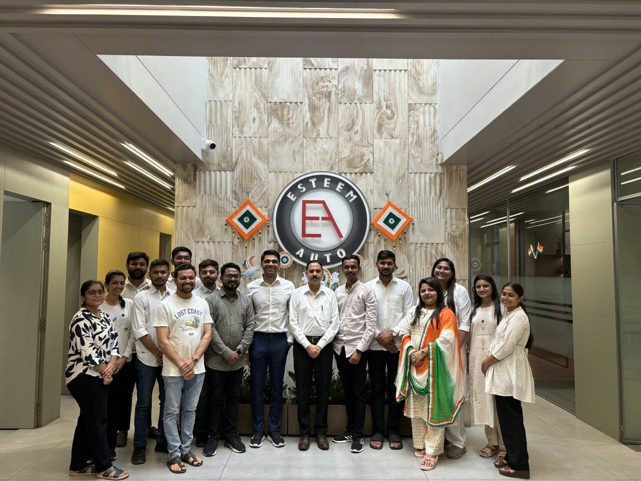 The Esteem Auto team in front of the company logo wall